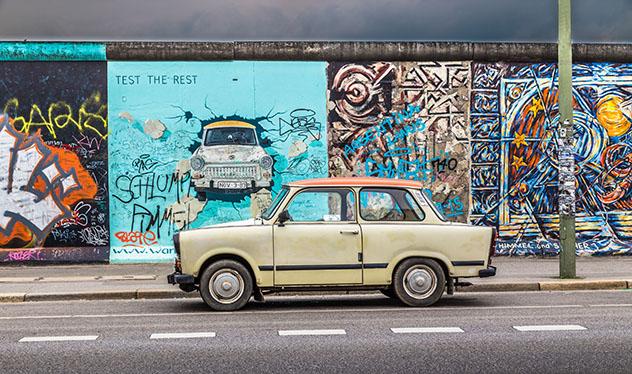 Turismo sostenible: comunidad. Un antiguo Trabant aparcado frente al Muro de Berlín en la East Side Gallery