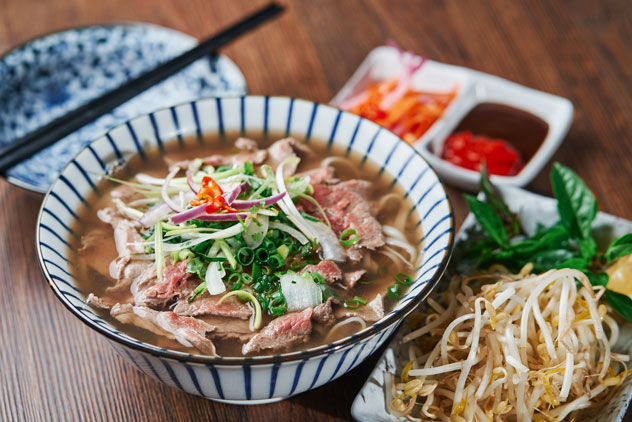 Plato de pho acompañado de otros platos. © fotobycam/Shutterstock