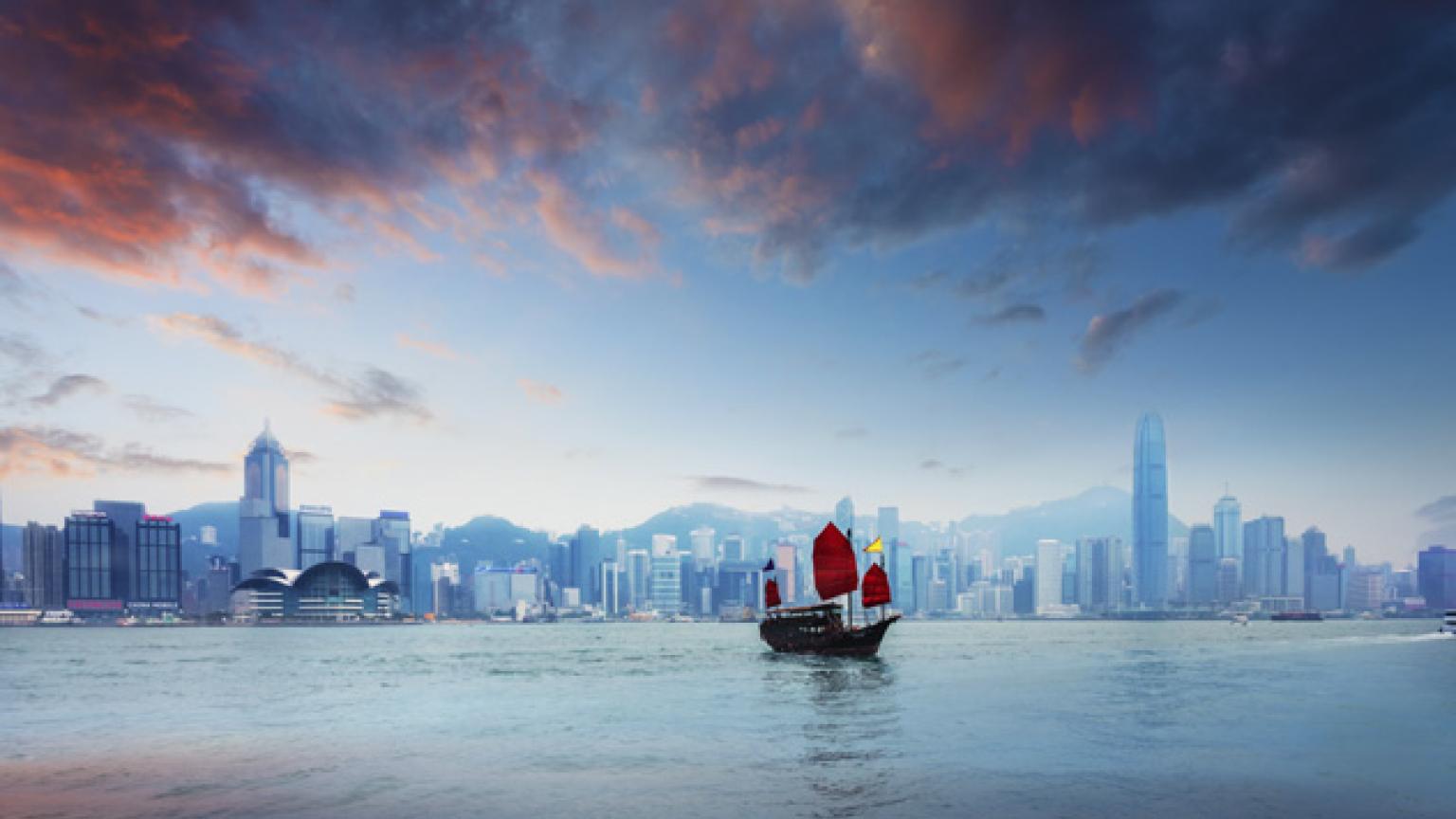 Barcos tradicionales de bambú navegan al anochecer en el Victoria Harbour, en Hong Kong
