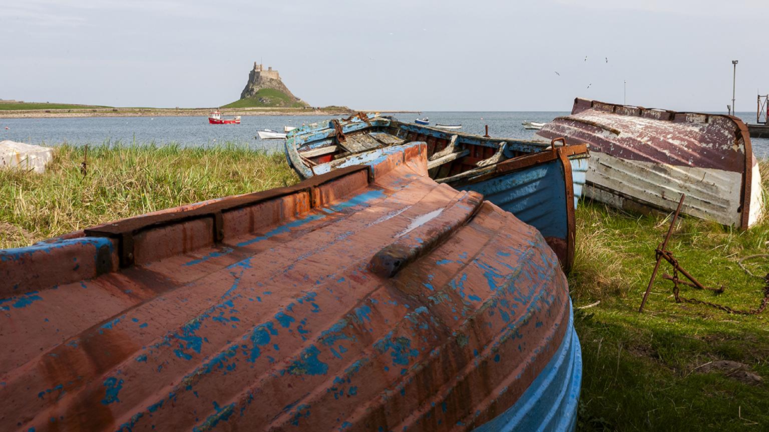 Barcos de pesca se alinean en la orilla cerca del castillo de Lindisfarne.