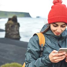Viajera con smartphone en Kirkjufjara, Islandia