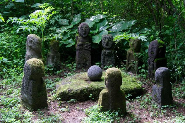 Estatuas de espíritus locales en un claro del bosque del Parque de Rocas de Jeju, Corea del Sur © Simon Richmond / Lonely Planet
