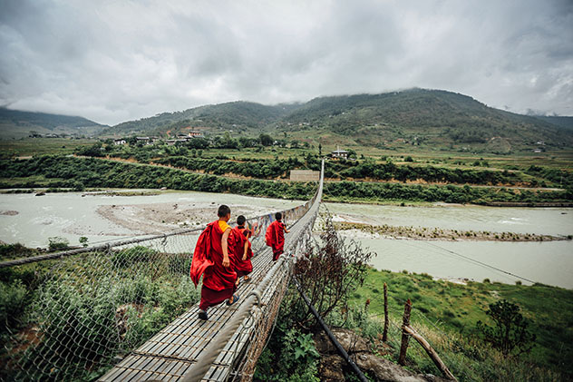 Viajar a Bután: monjes cruzando un puente