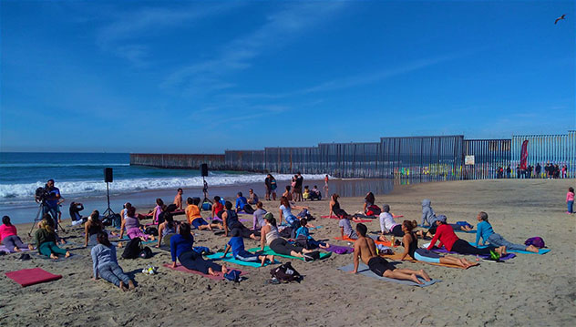 Familias que van de pícnic y aficionados al yoga practicando en la playa, a la sombra de la frontera, Tijuana, México © Jason Najum / Lonely Planet