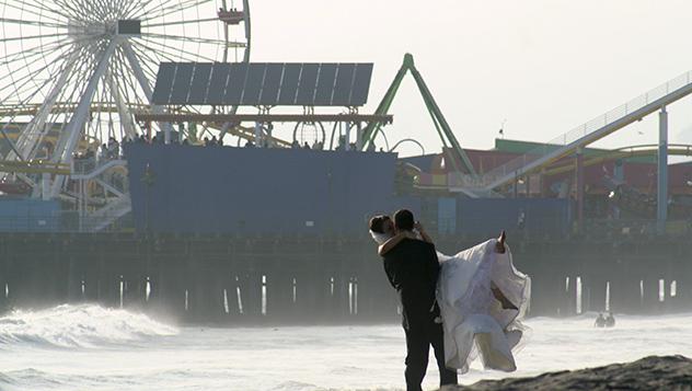 Pareja de recién casados con el muelle de Santa Mónica al fondo, California, Estados Unidos