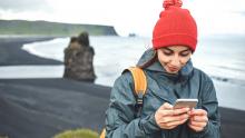 Viajera con smartphone en Kirkjufjara, Islandia