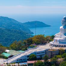 Vista Aéreas de la estatua del Gran Buda en una colina verde en Phuket, Tailandia, con senderos, estructuras circundantes y el mar de Andamán al fondo.