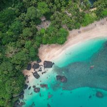 Vista aérea de las aguas cristalinas rodeadas de palmeras en Banana Beach, en la isla Príncipe, Santo Tomé, África.