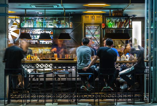 Gente sentada en taburetes y comiendo en la barra de un bar de Singapur © ZDL / Shutterstock